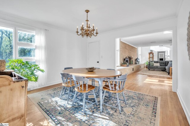 dining room with baseboards, ornamental molding, an inviting chandelier, and light wood-style floors
