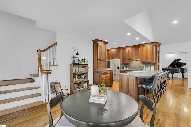 dining area with stairs, vaulted ceiling, recessed lighting, and light wood finished floors