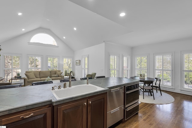 kitchen with open floor plan, tile counters, recessed lighting, dark wood-type flooring, and a sink