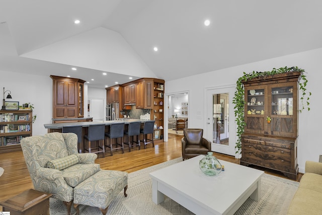 living area featuring high vaulted ceiling, light wood-style floors, and recessed lighting