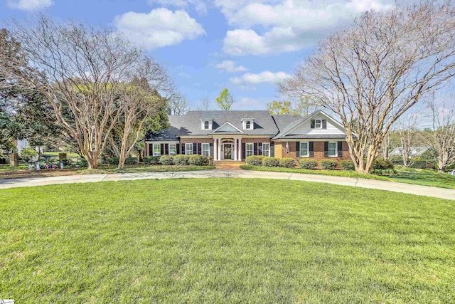 view of front facade featuring a front yard, brick siding, and curved driveway