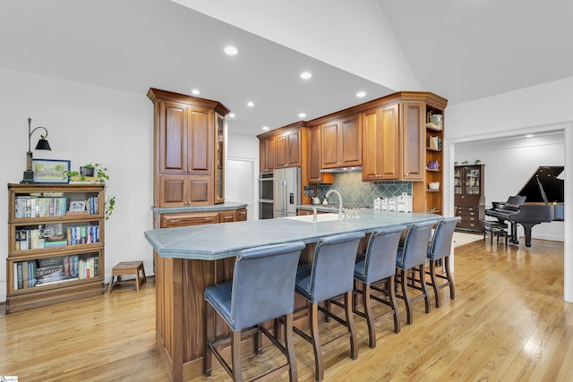 kitchen featuring open shelves, a breakfast bar area, a peninsula, tile countertops, and decorative backsplash
