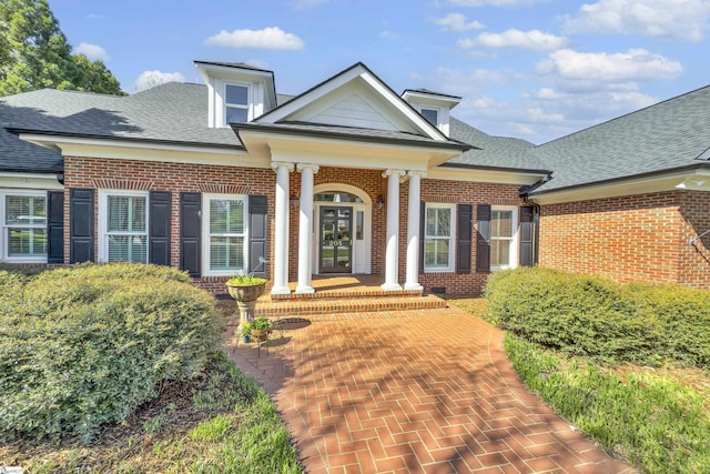neoclassical / greek revival house featuring french doors, brick siding, and a shingled roof