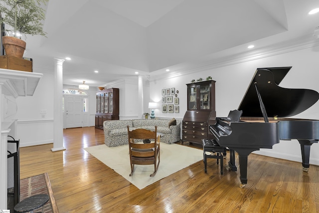 living area featuring recessed lighting, hardwood / wood-style floors, ornate columns, ornamental molding, and baseboards