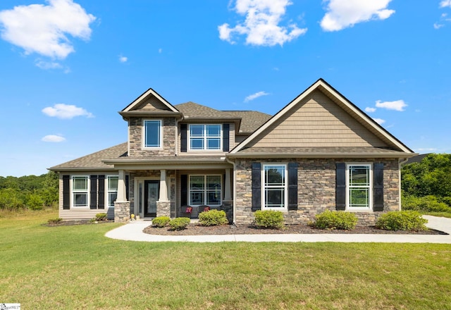 craftsman house featuring a front yard, stone siding, and roof with shingles