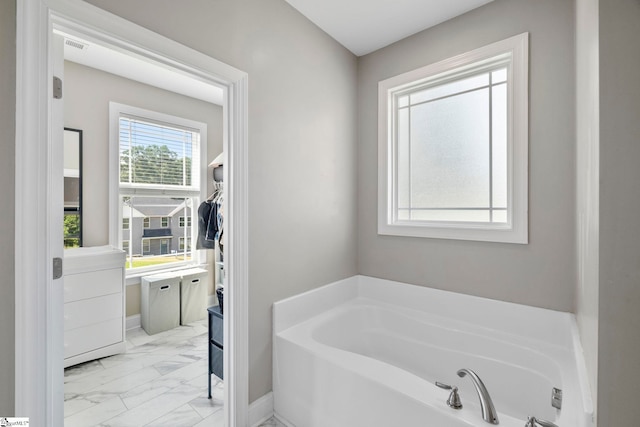 bathroom featuring marble finish floor, baseboards, a garden tub, and visible vents