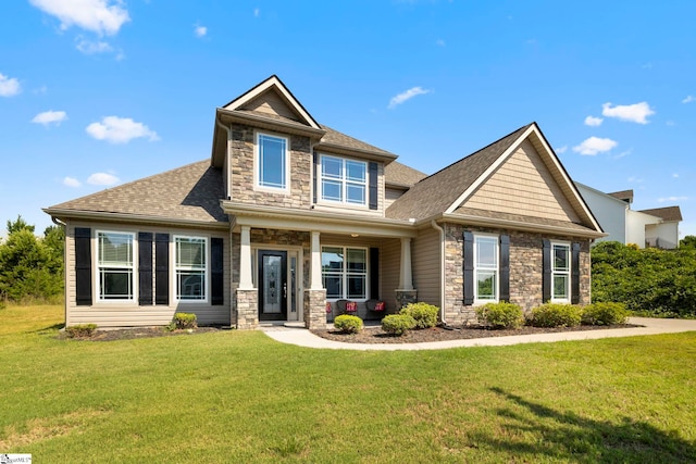 craftsman inspired home with stone siding, a front lawn, and roof with shingles