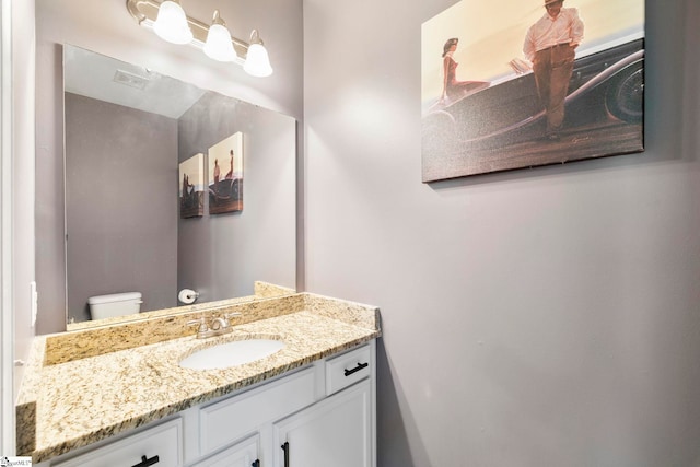 bathroom featuring visible vents, toilet, and vanity