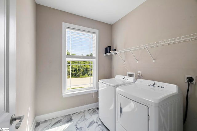 clothes washing area featuring baseboards, marble finish floor, laundry area, and washer and clothes dryer