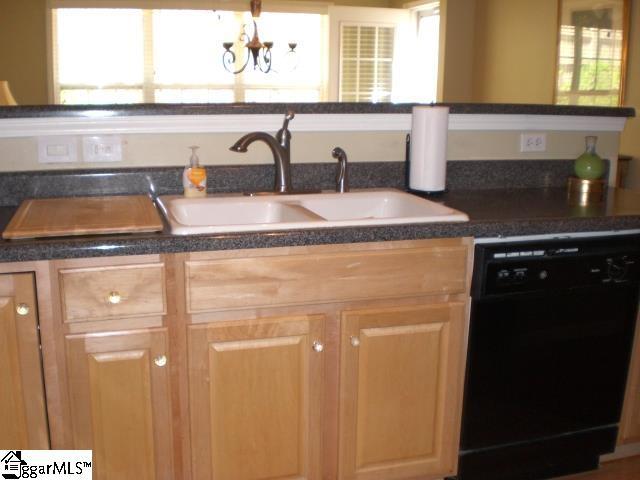 kitchen with an inviting chandelier, a sink, dark countertops, and black dishwasher