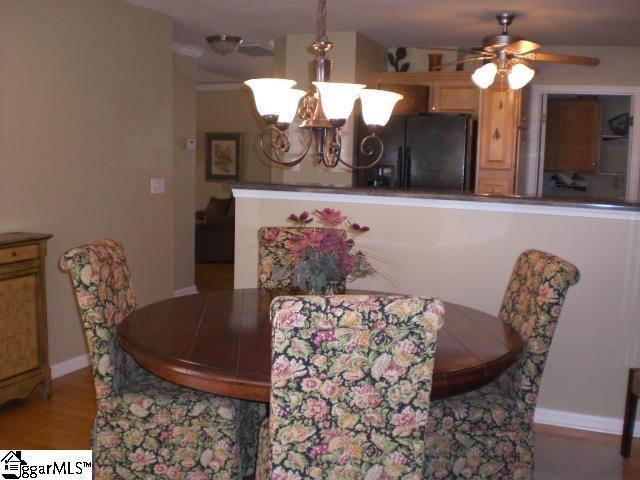 dining space with ceiling fan with notable chandelier, baseboards, and wood finished floors