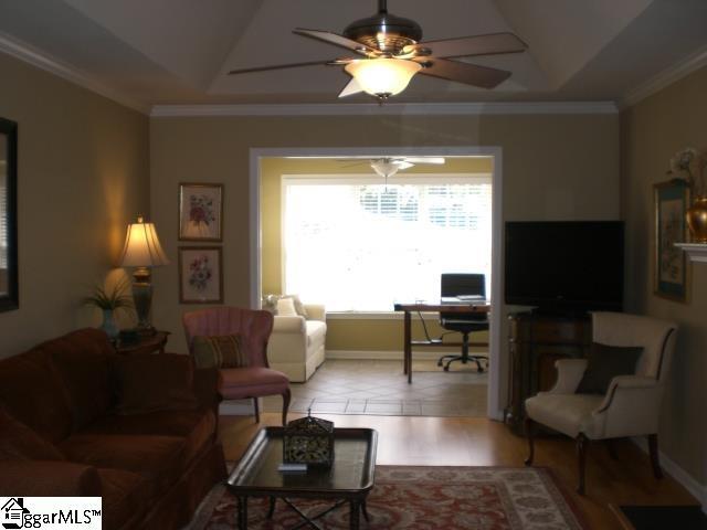 living room featuring crown molding, ceiling fan, and a raised ceiling