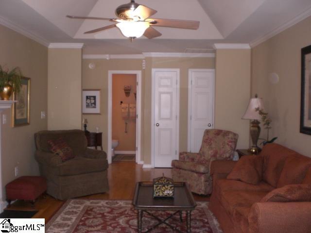 living area with wood finished floors, ceiling fan, and ornamental molding