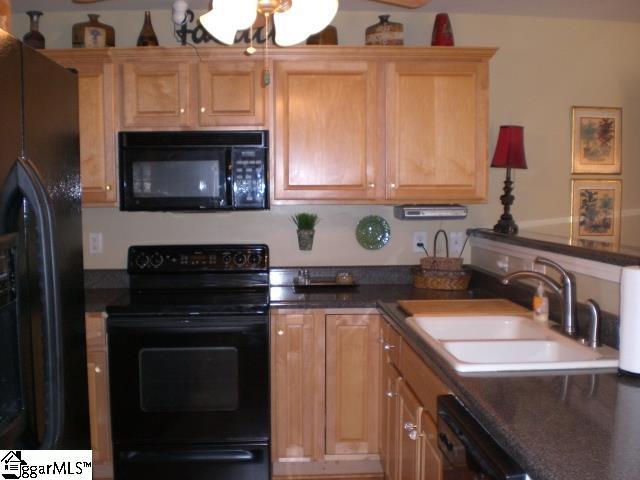 kitchen with a sink, black appliances, dark countertops, and a ceiling fan