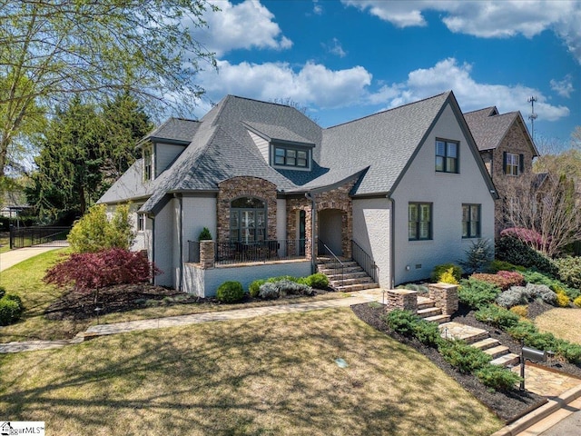 view of front of property featuring covered porch, brick siding, a front yard, and a shingled roof