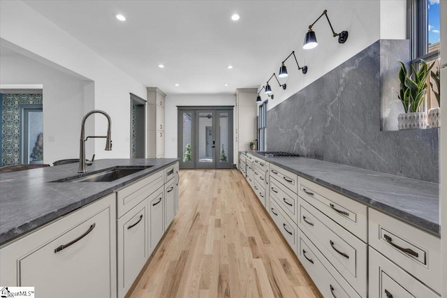 kitchen featuring tasteful backsplash, recessed lighting, gas cooktop, a sink, and light wood-style floors