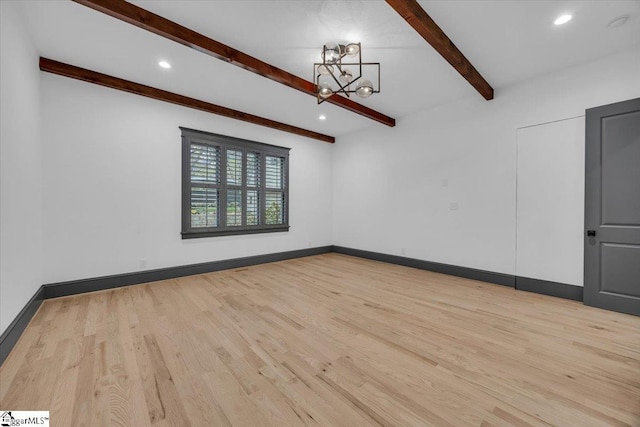 spare room featuring an inviting chandelier, beam ceiling, baseboards, and light wood finished floors