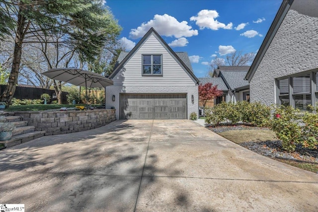view of property exterior featuring concrete driveway, fence, and an attached garage