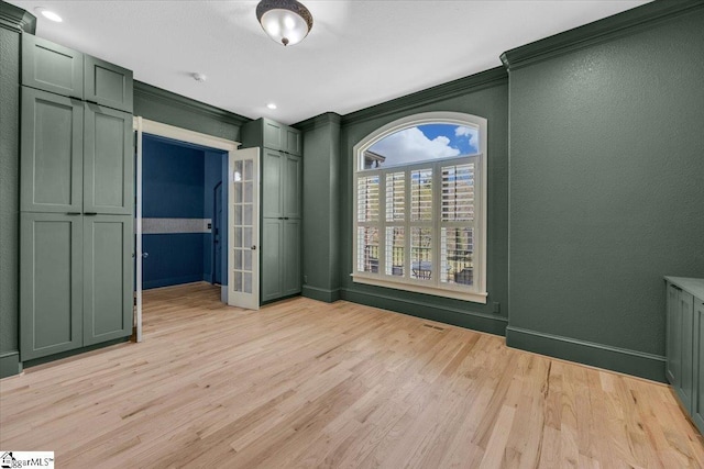 spare room with light wood-style flooring, crown molding, and baseboards