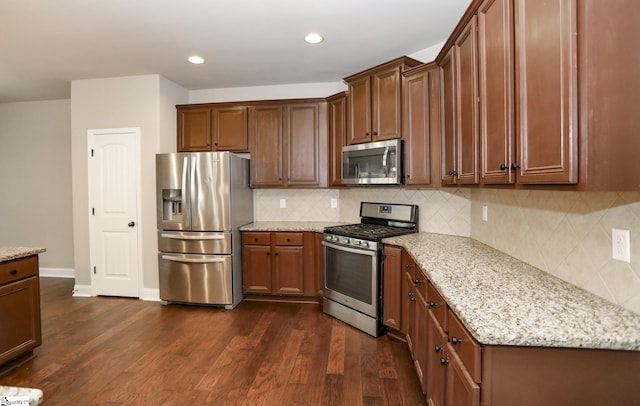 kitchen featuring recessed lighting, stainless steel appliances, decorative backsplash, dark wood finished floors, and light stone counters