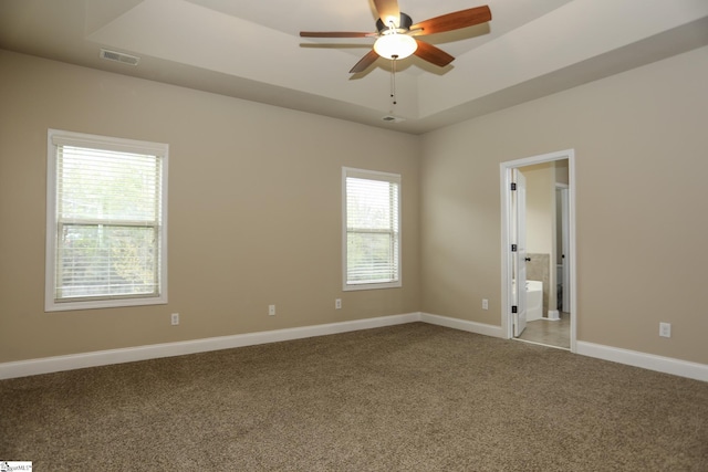 spare room featuring carpet flooring, baseboards, a raised ceiling, visible vents, and a ceiling fan