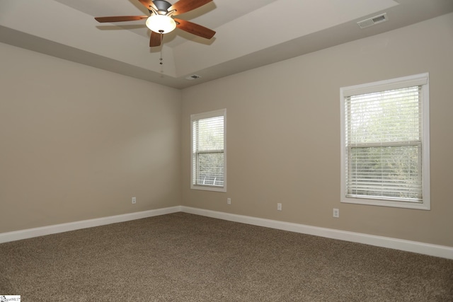 unfurnished room with baseboards, dark carpet, and visible vents