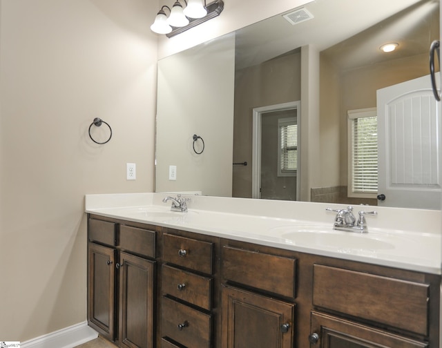 full bathroom featuring baseboards, visible vents, a sink, and double vanity