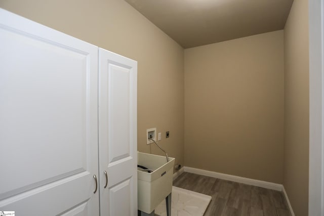 clothes washing area featuring electric dryer hookup, baseboards, laundry area, and dark wood finished floors