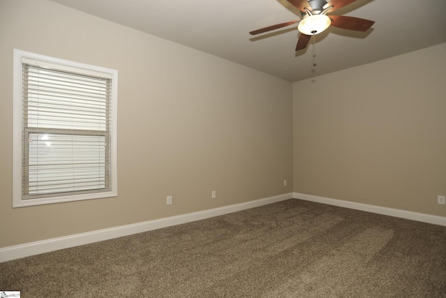 spare room with baseboards, ceiling fan, and dark carpet