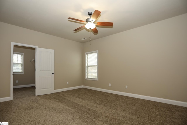 carpeted empty room featuring baseboards and a ceiling fan