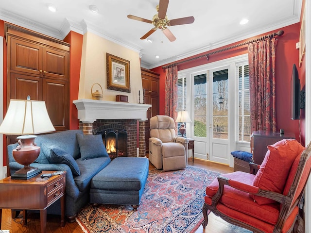 living room featuring crown molding, ceiling fan, wood finished floors, and a brick fireplace