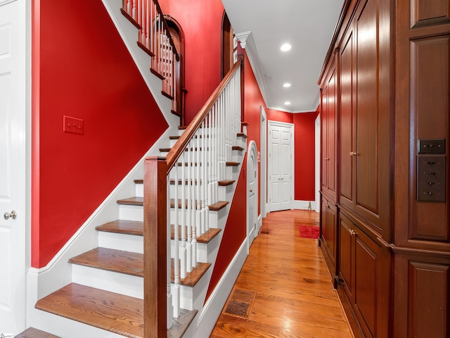 stairway with wood finished floors, baseboards, visible vents, ornamental molding, and recessed lighting