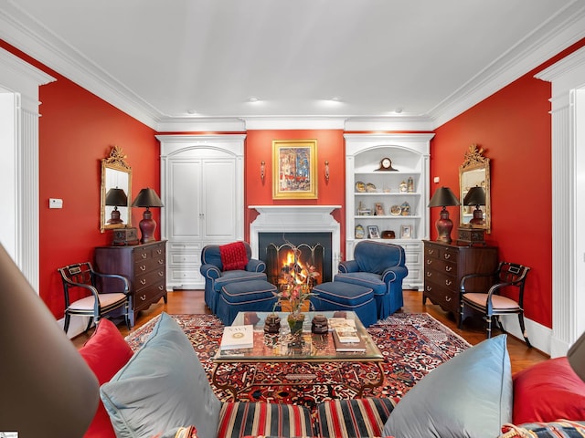 living area featuring a warm lit fireplace, wood finished floors, ornamental molding, and built in shelves