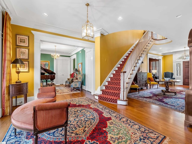 living area featuring crown molding, wood finished floors, stairway, and a notable chandelier