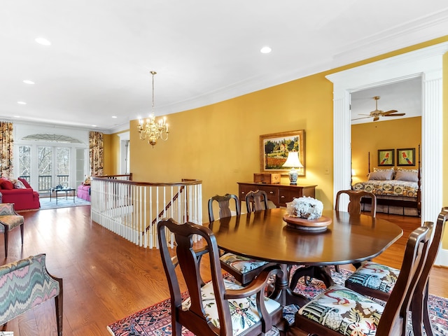 dining area with ceiling fan with notable chandelier, crown molding, wood finished floors, and recessed lighting
