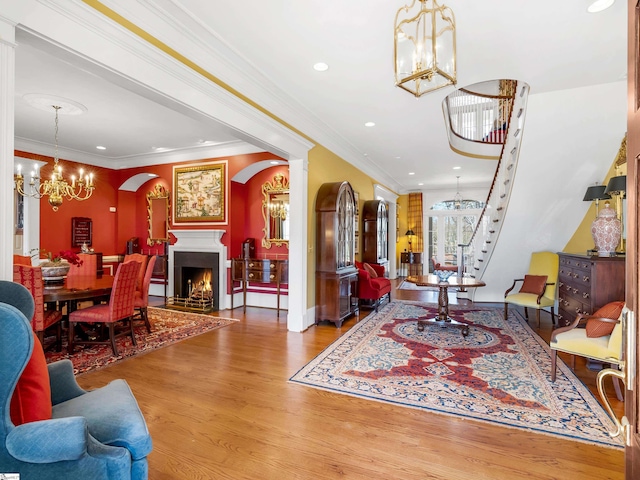 living room featuring arched walkways, wood finished floors, a chandelier, and crown molding
