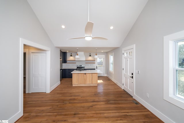 kitchen featuring light countertops, wood finished floors, light brown cabinets, a kitchen island, and stainless steel range