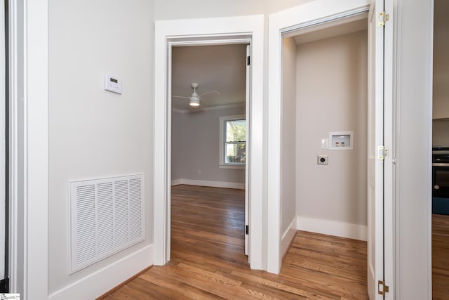 corridor with light wood-style floors, visible vents, and baseboards