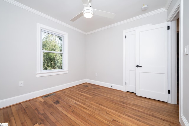 spare room with ceiling fan, light wood finished floors, baseboards, ornamental molding, and visible vents