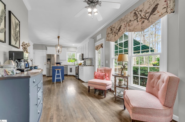sitting room with crown molding, ceiling fan, and wood finished floors
