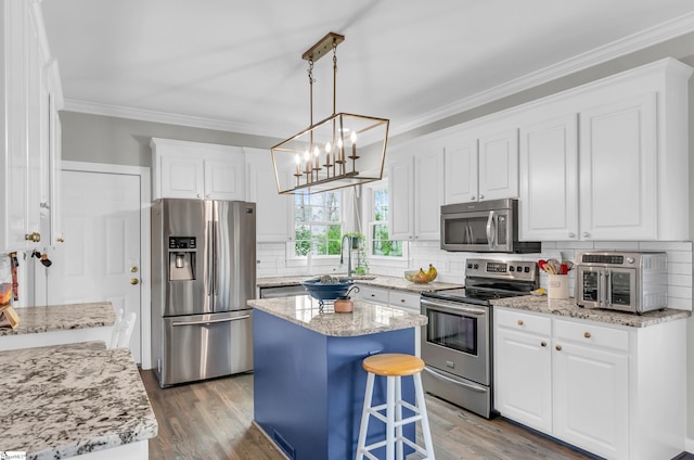 kitchen with crown molding, a sink, light wood-type flooring, stainless steel appliances, and decorative backsplash