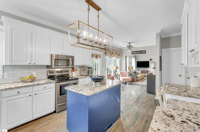 kitchen with ornamental molding, ceiling fan, stainless steel appliances, white cabinetry, and backsplash