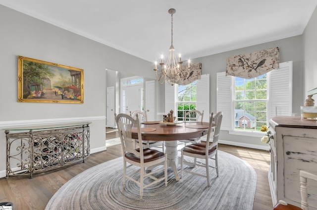 dining room with ornamental molding, a notable chandelier, baseboards, and wood finished floors