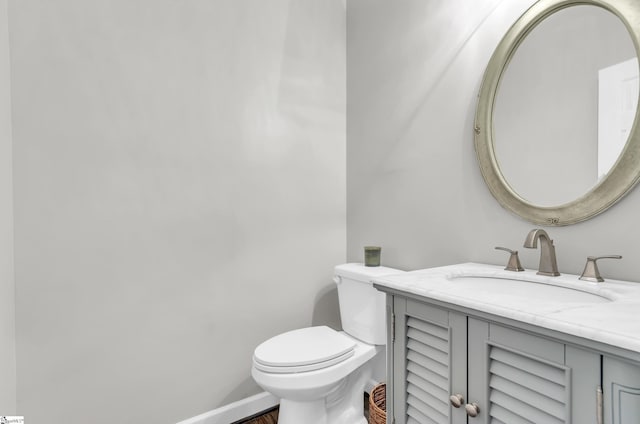 half bath with baseboards, toilet, and vanity