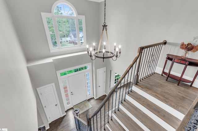 entryway with baseboards, wood finished floors, stairway, a high ceiling, and a notable chandelier