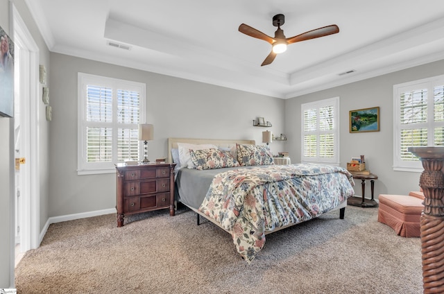 carpeted bedroom featuring a tray ceiling, multiple windows, and visible vents