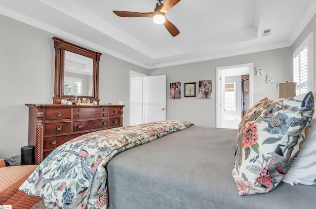 bedroom featuring visible vents, crown molding, a ceiling fan, a raised ceiling, and carpet floors