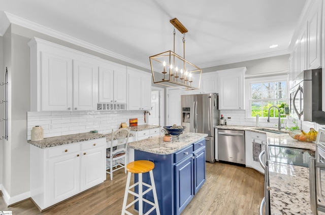 kitchen featuring a sink, ornamental molding, appliances with stainless steel finishes, and blue cabinetry