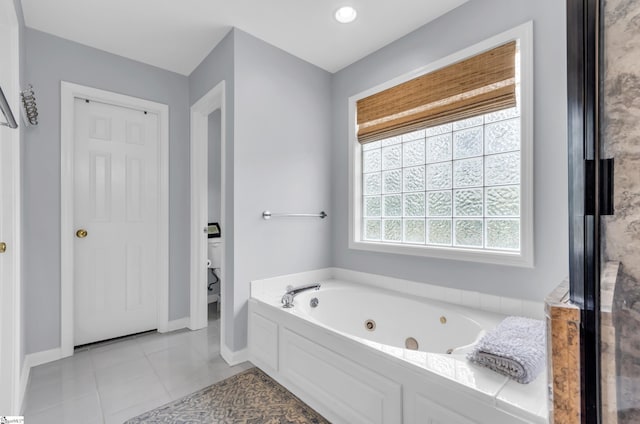 full bathroom featuring a tub with jets, tile patterned floors, toilet, and baseboards