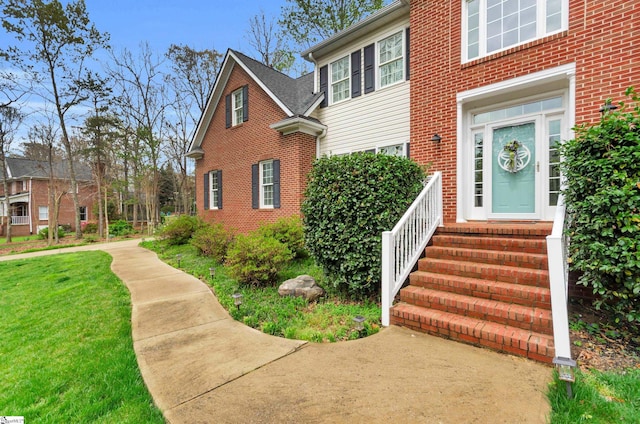 exterior space featuring brick siding and a front yard